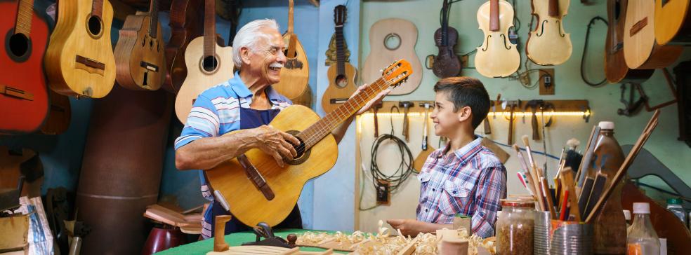 senior man teaching grandson the guitar